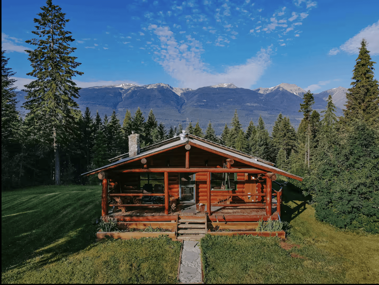 Log Cabin in Golden, BC surrounded by forests with mountains in the background